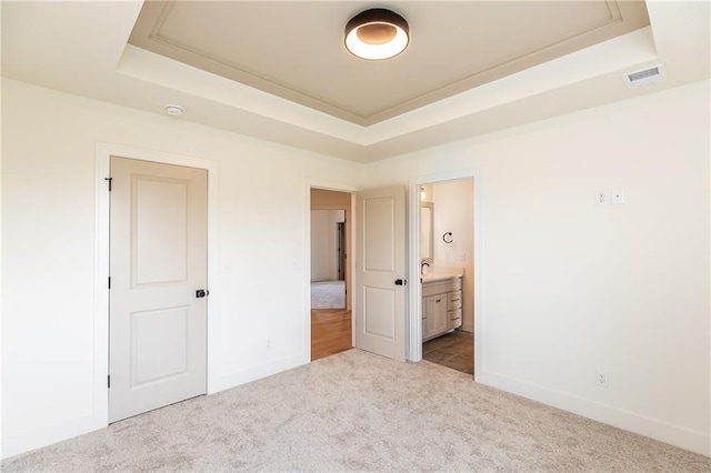 18505 Mohawk Ln, Overland Park, KS 66085 - unfurnished bedroom with a tray ceiling, carpet flooring, and connected bathroom