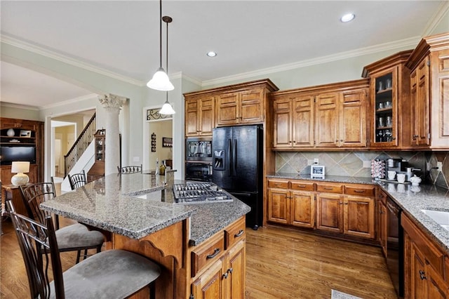 5716 W 146th St, Overland Park, KS 66223 - kitchen featuring black appliances, decorative columns, brown cabinetry, a breakfast bar, and wood finished floors