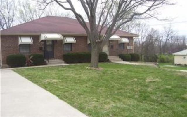 1019 N Kiger Rd, Independence, MO 64050 - view of front of home featuring a front yard, concrete driveway, and brick siding