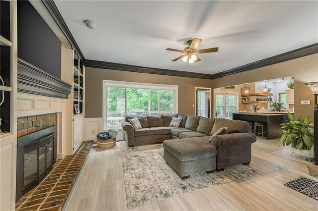617 Butternut Ln, Liberty, MO 64068 - living area featuring a fireplace, ornamental molding, a ceiling fan, wood finished floors, and wainscoting
