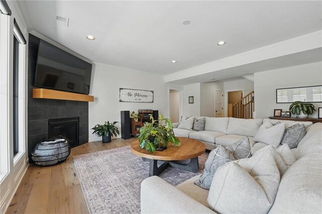 17316 Noland St, Overland Park, KS 66221 - living room featuring stairway, light wood-style floors, recessed lighting, and a tiled fireplace