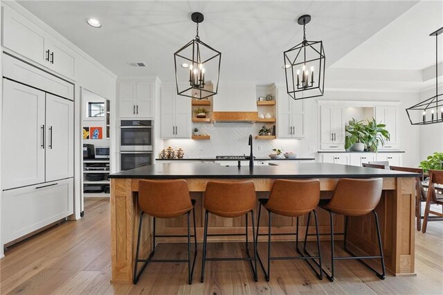17316 Noland St, Overland Park, KS 66221 - kitchen with stainless steel appliances, open shelves, a chandelier, dark countertops, and decorative backsplash