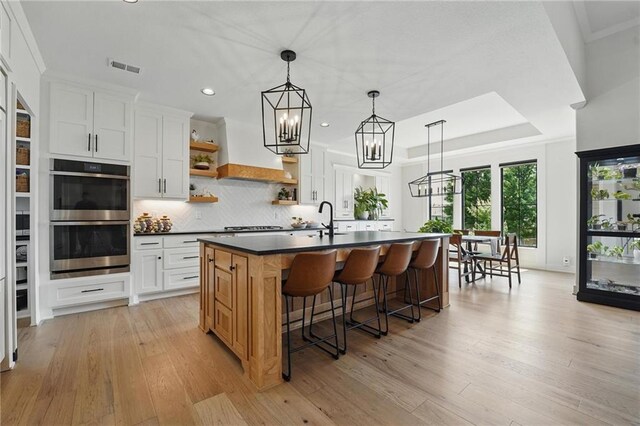 17316 Noland St, Overland Park, KS 66221 - kitchen with stainless steel double oven, dark countertops, open shelves, recessed lighting, and light wood finished floors