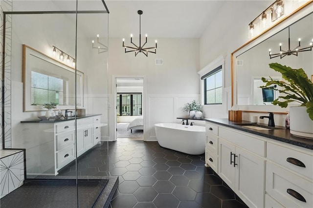 17316 Noland St, Overland Park, KS 66221 - bathroom with a chandelier, two vanities, a high ceiling, a freestanding bath, and a wainscoted wall