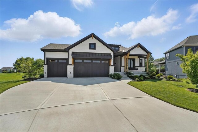 17316 Noland St, Overland Park, KS 66221 - view of front facade featuring an attached garage, a front yard, concrete driveway, covered porch, and a standing seam roof