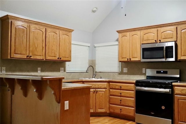 15714 Richmond Ave, Belton, MO 64012 - kitchen with stainless steel appliances, light wood finished floors, backsplash, a breakfast bar, and light countertops