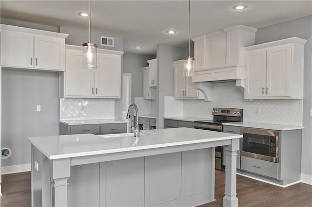 19787 W 114th Pl, Olathe, KS 66061 - kitchen featuring electric stove, built in microwave, dark wood finished floors, an island with sink, and light countertops