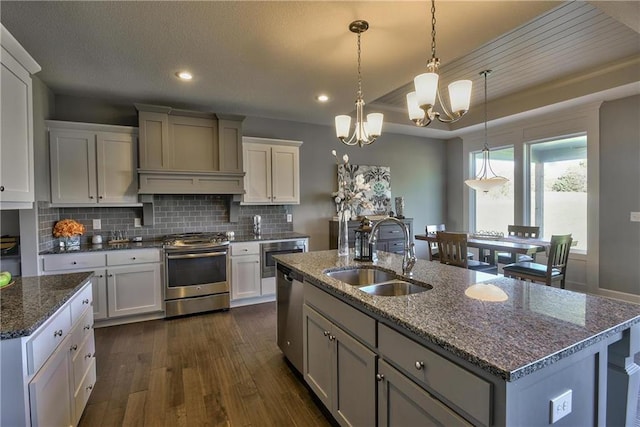 19787 W 114th Pl, Olathe, KS 66061 - kitchen with stainless steel appliances, custom exhaust hood, a chandelier, an island with sink, and dark wood finished floors