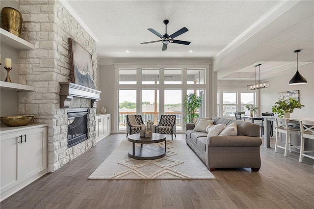 19499 W 114th Ter, Olathe, KS 66061 - living area featuring ceiling fan, a stone fireplace, wood finished floors, crown molding, and a textured ceiling