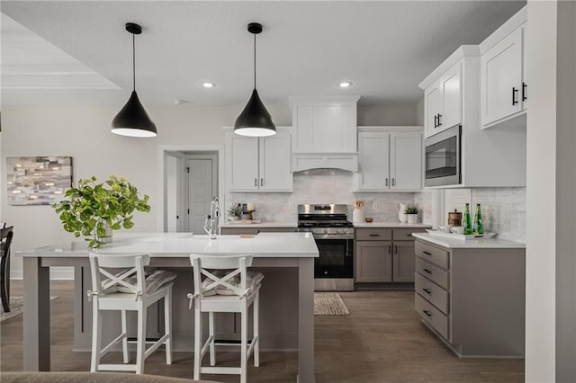 19499 W 114th Ter, Olathe, KS 66061 - kitchen with appliances with stainless steel finishes, light countertops, decorative backsplash, dark wood-style floors, and a center island with sink