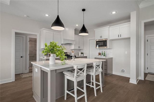 19499 W 114th Ter, Olathe, KS 66061 - kitchen with dark wood-type flooring, tasteful backsplash, light countertops, a kitchen island with sink, and white cabinetry