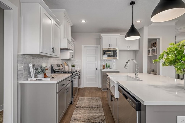 19499 W 114th Ter, Olathe, KS 66061 - kitchen with appliances with stainless steel finishes, light countertops, dark wood-style flooring, backsplash, and hanging light fixtures