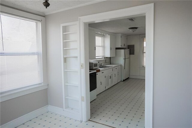 1101 S Broadway St, Leavenworth, KS 66048 - kitchen with range with electric stovetop, stainless steel microwave, light flooring, white cabinets, and light countertops