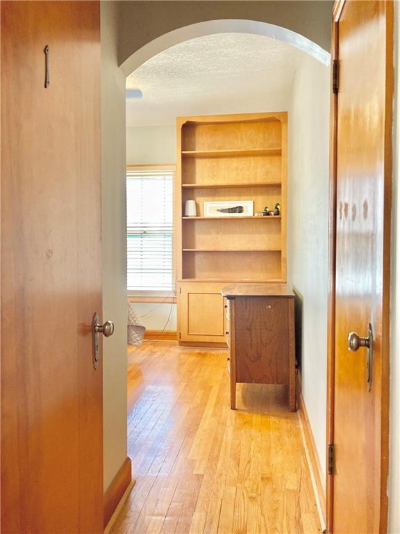 406 S 6th St, Burlington, KS 66839 - corridor featuring arched walkways, light wood finished floors, and a textured ceiling