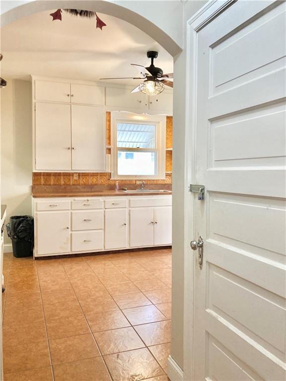406 S 6th St, Burlington, KS 66839 - kitchen featuring ceiling fan, arched walkways, light tile patterned floors, and white cabinetry