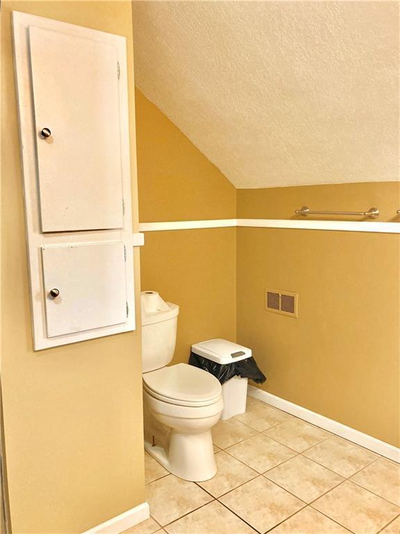 406 S 6th St, Burlington, KS 66839 - bathroom featuring a textured ceiling, tile patterned floors, and vaulted ceiling