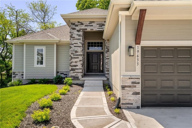 19345 W 114th Ter, Olathe, KS 66061 - property entrance featuring stone siding, an attached garage, roof with shingles, and a lawn