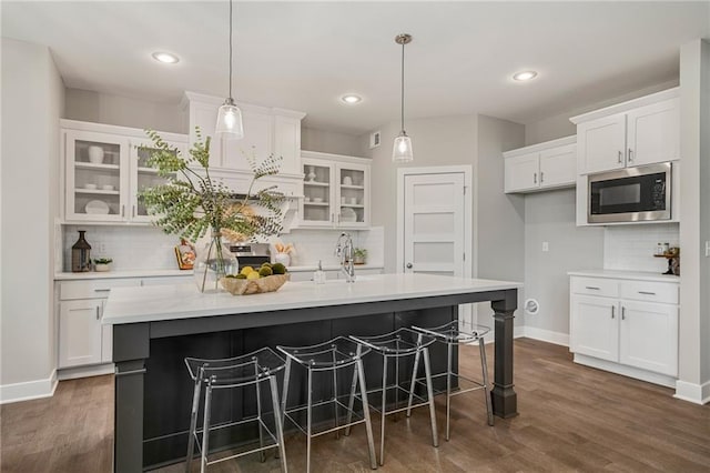 19345 W 114th Ter, Olathe, KS 66061 - kitchen featuring stainless steel microwave, backsplash, white cabinetry, light countertops, and glass insert cabinets