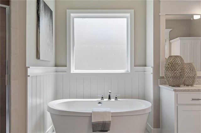 19345 W 114th Ter, Olathe, KS 66061 - bathroom with a decorative wall, a freestanding tub, a wainscoted wall, and vanity