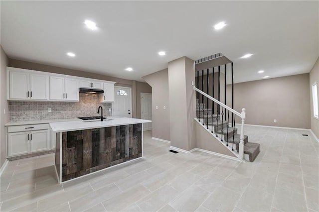 605 Oak St, Leavenworth, KS 66048 - kitchen featuring under cabinet range hood, white cabinetry, decorative backsplash, light countertops, and recessed lighting