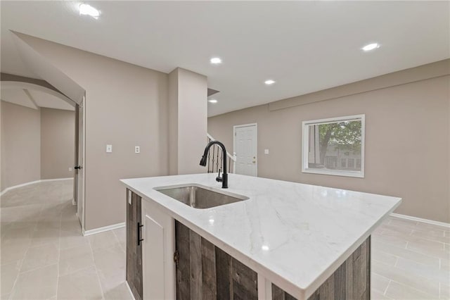 605 Oak St, Leavenworth, KS 66048 - kitchen with light stone counters, a kitchen island with sink, recessed lighting, and arched walkways