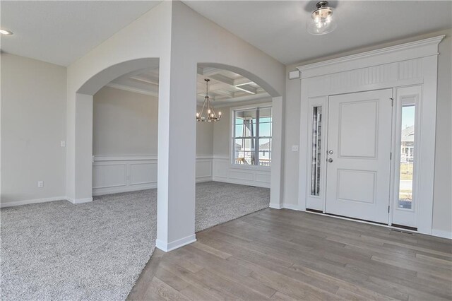 19466 W 114th Ter, Olathe, KS 66061 - foyer entrance featuring arched walkways, a chandelier, coffered ceiling, wood finished floors, and beamed ceiling