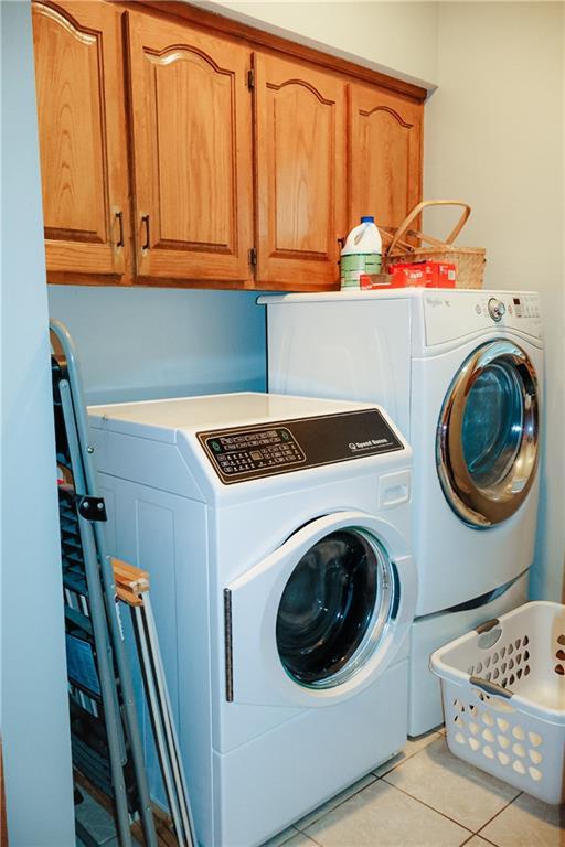 11669 S Parkwood Dr, Olathe, KS 66061 - laundry area with washing machine and dryer, cabinet space, and light tile patterned floors