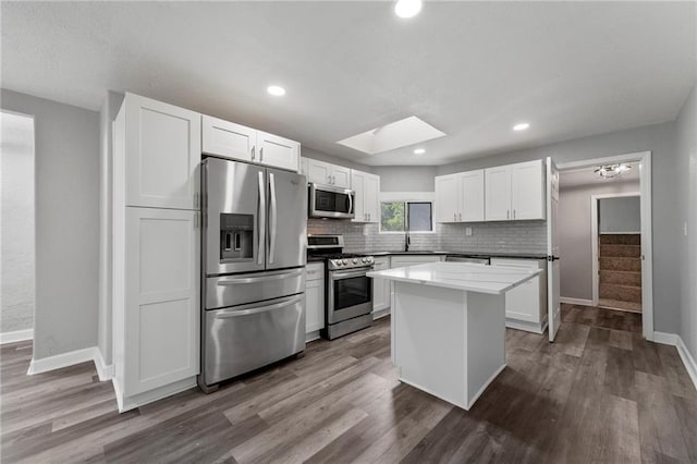 2101 Spruce St, Leavenworth, KS 66048 - kitchen with appliances with stainless steel finishes, tasteful backsplash, dark wood finished floors, white cabinetry, and recessed lighting