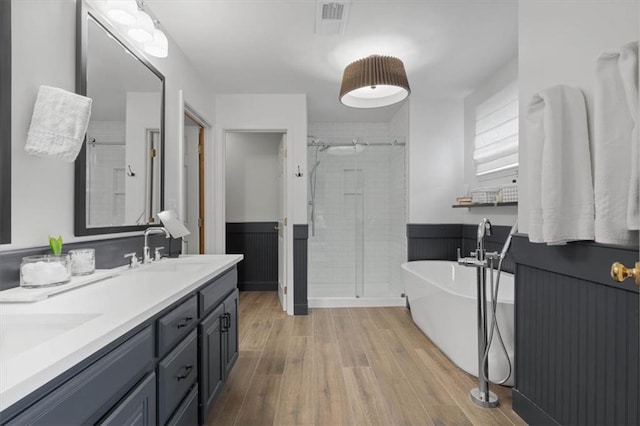 12499 S Marion St, Olathe, KS 66061 - bathroom featuring a shower stall, a soaking tub, wainscoting, double vanity, and wood finished floors