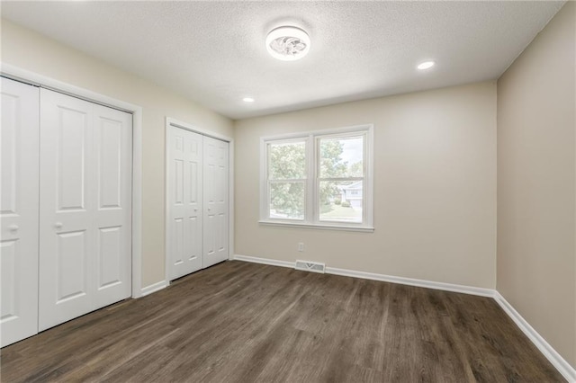 729 S Central St, Olathe, KS 66061 - unfurnished bedroom featuring multiple closets, dark wood-style floors, a textured ceiling, and recessed lighting