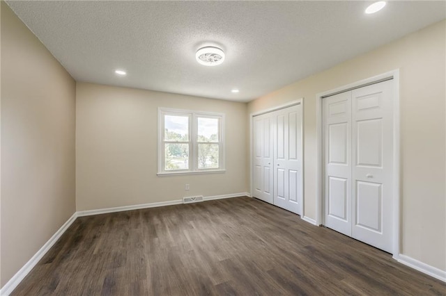729 S Central St, Olathe, KS 66061 - unfurnished bedroom featuring two closets, dark wood-type flooring, a textured ceiling, and recessed lighting