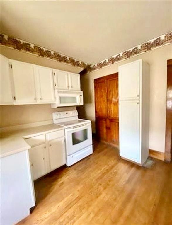 320 W Walnut St, Nevada, MO 64772 - kitchen featuring white appliances, white cabinetry, light wood-style floors, and light countertops