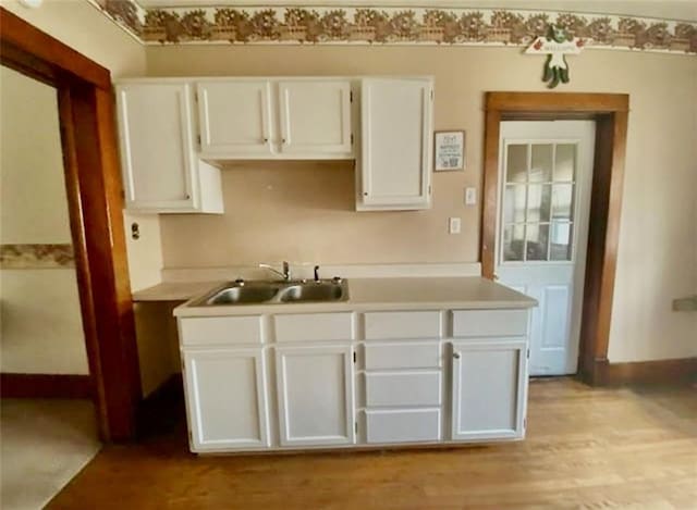 320 W Walnut St, Nevada, MO 64772 - kitchen with white cabinetry, light wood-style floors, and light countertops