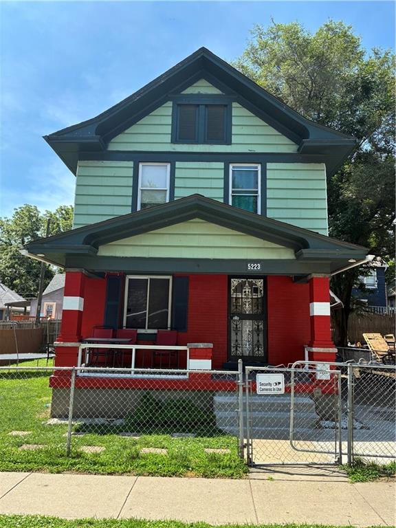 5223 Wilburn Ct, Kansas City, MO 64123 - american foursquare style home with covered porch, a fenced front yard, and a gate