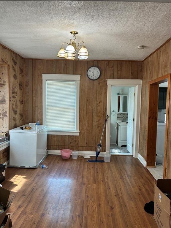 5223 Wilburn Ct, Kansas City, MO 64123 - dining space with wood walls, wood finished floors, a chandelier, and a textured ceiling