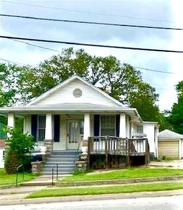 326 W Walnut St, Nevada, MO 64772 - view of front facade featuring a porch, a detached garage, an outdoor structure, and driveway