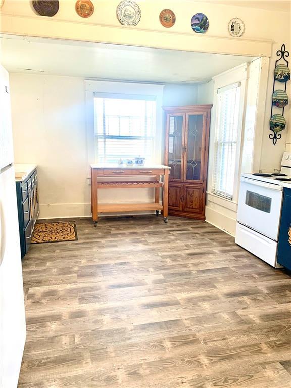 326 W Walnut St, Nevada, MO 64772 - kitchen featuring white electric range oven, healthy amount of natural light, and light wood finished floors