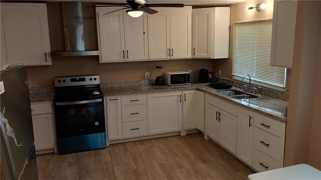 107 N 20th St, Leavenworth, KS 66048 - kitchen featuring stainless steel electric range, wall chimney range hood, ceiling fan, freestanding refrigerator, and black microwave
