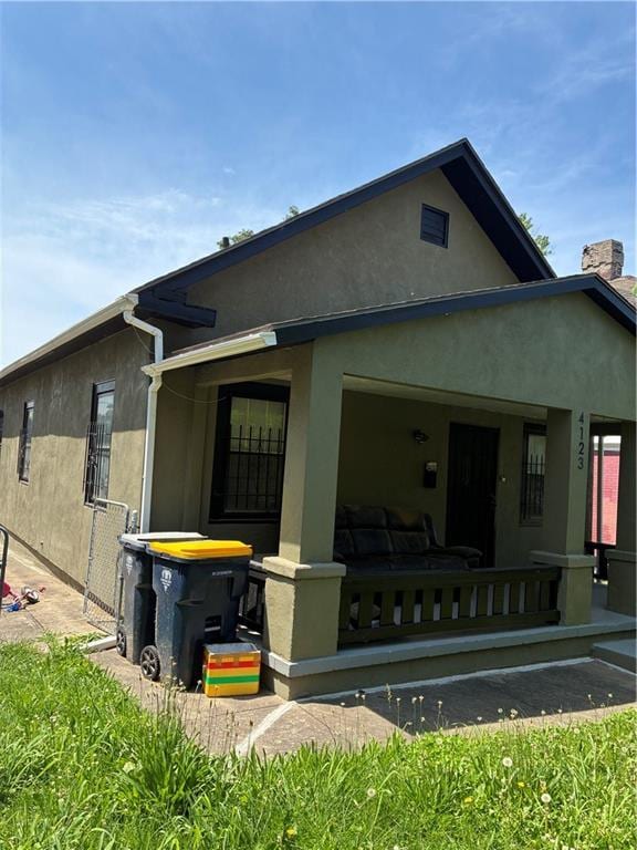 4123 E 6th St, Kansas City, MO 64124 - view of front facade with a porch, stucco siding, and a chimney