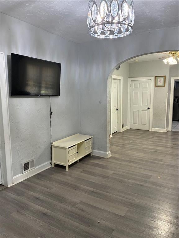 4123 E 6th St, Kansas City, MO 64124 - unfurnished living room with arched walkways, dark wood-style flooring, a ceiling fan, and a chandelier