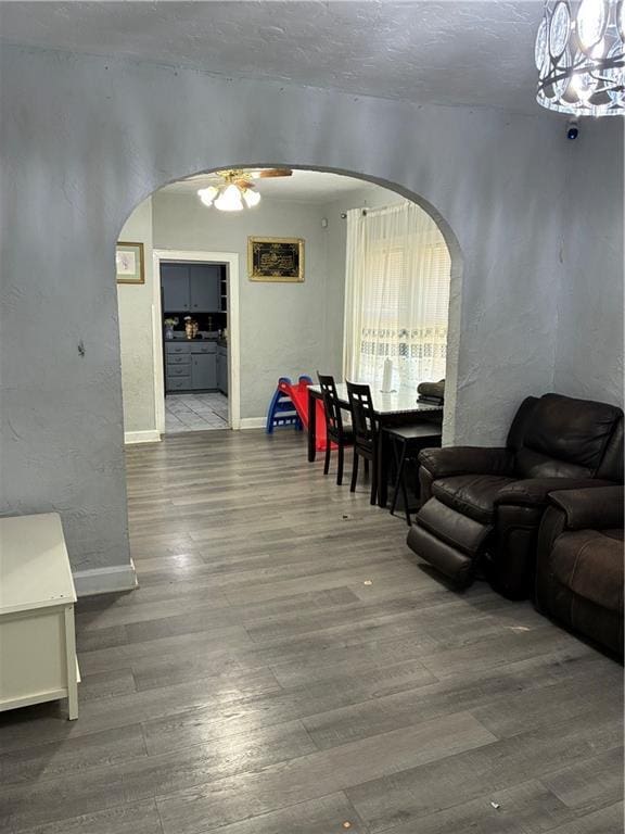 4123 E 6th St, Kansas City, MO 64124 - living area featuring arched walkways, wood finished floors, a ceiling fan, a chandelier, and a textured wall