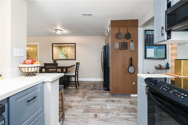 118 Village St, Tonganoxie, KS 66086 - kitchen with black appliances, light wood-type flooring, and light countertops