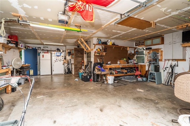 118 Village St, Tonganoxie, KS 66086 - garage featuring freestanding refrigerator, a garage door opener, and a workshop area