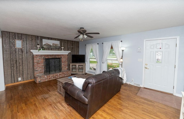 106 S Clark St, Adrian, MO 64720 - living room with a ceiling fan, wood finished floors, a fireplace, and wood walls