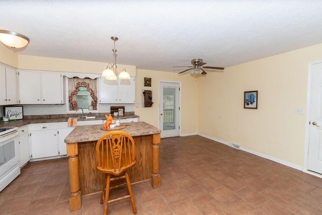 106 S Clark St, Adrian, MO 64720 - kitchen with electric stove, a center island, a ceiling fan, and white cabinetry