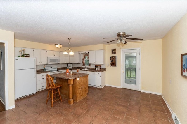 106 S Clark St, Adrian, MO 64720 - kitchen with white appliances, dark countertops, a center island, white cabinets, and a textured ceiling