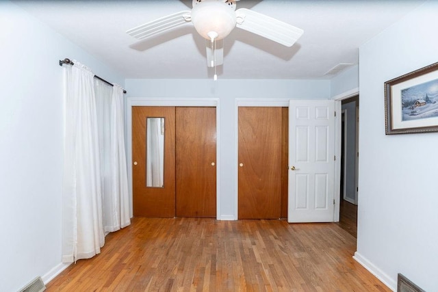 106 S Clark St, Adrian, MO 64720 - unfurnished bedroom featuring two closets, wood finished floors, and a ceiling fan