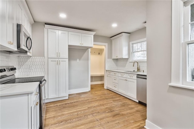 5740 Oak St, Kansas City, MO 64113 - kitchen with stainless steel appliances, white cabinetry, light wood-style flooring, tasteful backsplash, and light countertops