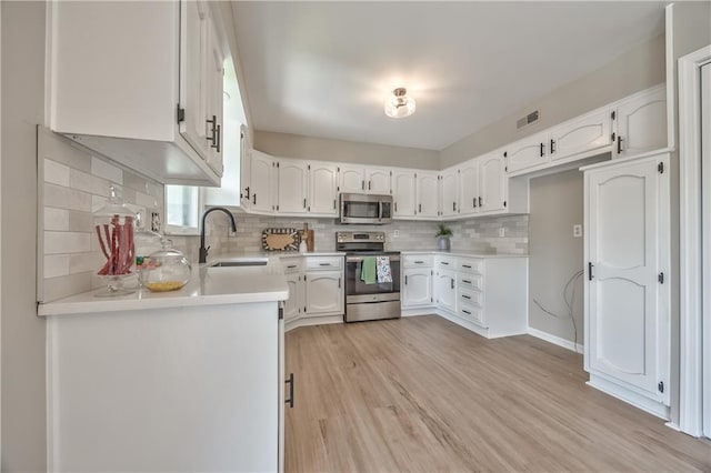 10706 W 50th Ter, Shawnee, KS 66203 - kitchen featuring appliances with stainless steel finishes, white cabinetry, light wood-style floors, and tasteful backsplash