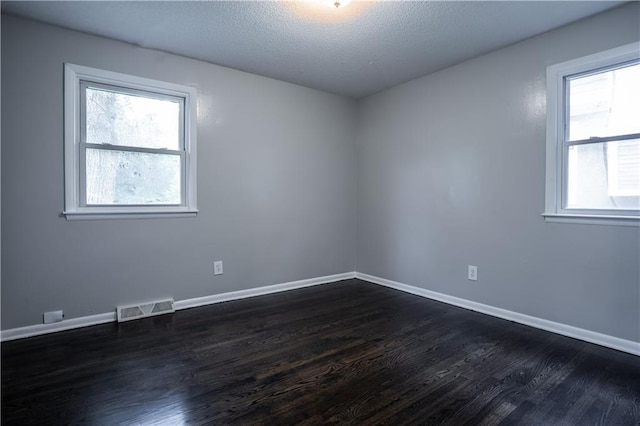 531 S Cedar Ave, Independence, MO 64053 - spare room with dark wood-style flooring, healthy amount of natural light, and a textured ceiling